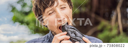 Man eating Vietnamese Pork Banh Mi Sandwich in a black baguette BANNER, LONG FORMAT 73808022