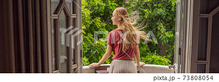 BANNER, LONG FORMAT A ginger-haired woman stands on a heritage-style balcony enjoying her morning coffee. A woman in a hotel in Europe or Asia as tourism recovers from a pandemic. Tourism has BANNER, LONG FORMAT A ginger-haired woman stands on a heritage-style balcony enjoying her morning coffee. A woman in a hotel in Europe or Asia as tourism recovers from a pandemic. Tourism has 73808054