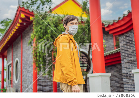 traveler in medical mask stopped on the street and looking at the Japanese, Chinese, Korean, Vietnamese traditional building. Tourists travel in Asia after the coronavirus epidemic traveler in medical mask stopped on the street and looking at the Japanese, Chinese, Korean, Vietnamese traditional building. Tourists travel in Asia after the coronavirus epidemic 73808356