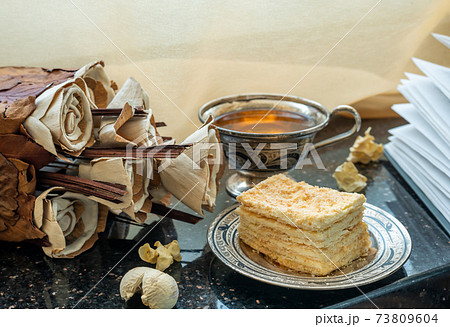 Homemade flowers from natural materials, Napoleon cake and a cup of tea on the windowsill. 73809604