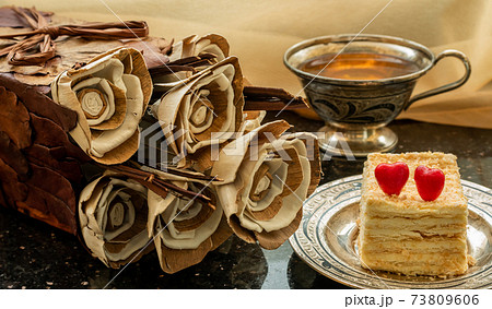 Homemade flowers from natural materials, Napoleon cake and a cup of tea on the windowsill. 73809606