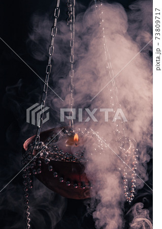 Magic session with a burning candle in a chained bowl and enveloping smoke Magic session with a burning candle in a chained bowl and enveloping smoke 73809717