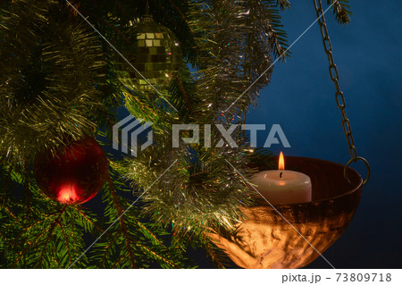Christmas decorations on a fir tree with a lit candle 73809718