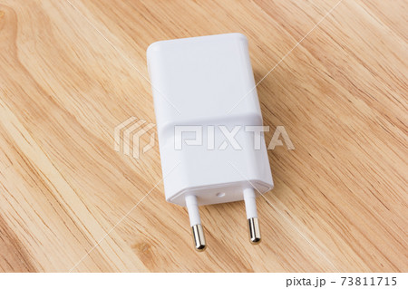 AC charger for smatphone. Charger for a smartphone in white on a wooden background. AC charger for smatphone. Charger for a smartphone in white on a wooden background. 73811715