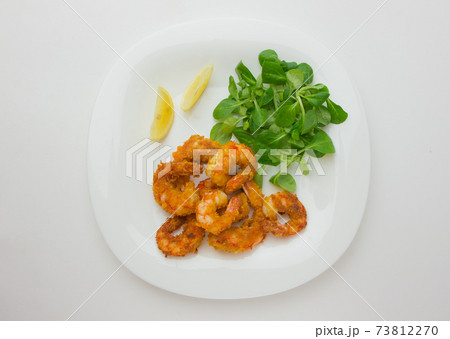 Fried shrimps on a plate. Prawns fried in breading on a white plate with salad and lemon. Fried shrimps on a plate. Prawns fried in breading on a white plate with salad and lemon. 73812270