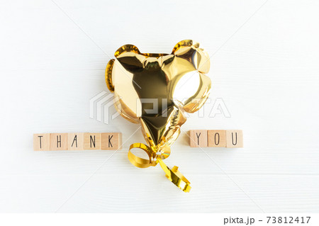 The word thank you on wooden cubes and a heart shaped balloon on a light background with space for text. Postcard, business card layout. 73812417