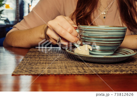 Cup of coffee on a wooden table, the girl holds her hand one cup of coffee . A photo depicting a melancholic mood Cup of coffee on a wooden table, the girl holds her hand one cup of coffee . A photo depicting a melancholic mood 73812626
