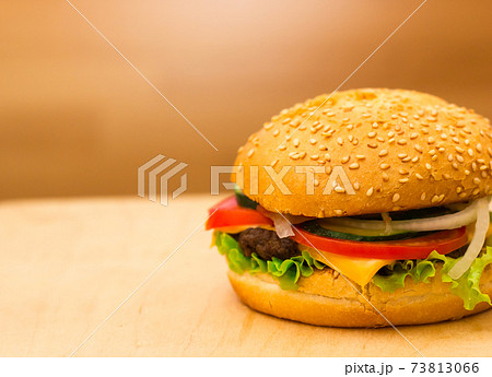 Burger close-up on a board. A burger with a meatball and fresh vegetables. Burger close-up on a board. A burger with a meatball and fresh vegetables. 73813066