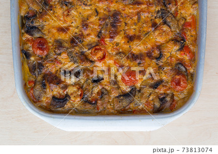 Casserole in a baking tray on a wooden table. The finished dish is baked in the oven. Casserole in a baking tray on a wooden table. The finished dish is baked in the oven. 73813074