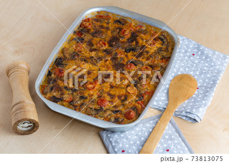 Casserole in a baking tray on a wooden table. The finished dish is baked in the oven. Casserole in a baking tray on a wooden table. The finished dish is baked in the oven. 73813075