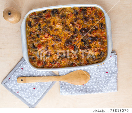 Casserole in a baking tray on a wooden table. The finished dish is baked in the oven. Casserole in a baking tray on a wooden table. The finished dish is baked in the oven. 73813076