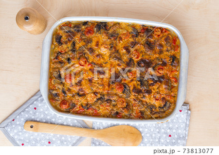 Casserole in a baking tray on a wooden table. The finished dish is baked in the oven. Casserole in a baking tray on a wooden table. The finished dish is baked in the oven. 73813077