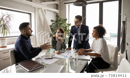 Diverse employees listening to Arabian colleague at meeting in boardroom Diverse employees listening to Arabian colleague at meeting in boardroom 73814411