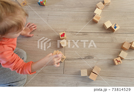 a child plays on the floor with wooden cubes. The view from the top a child plays on the floor with wooden cubes. The view from the top 73814529