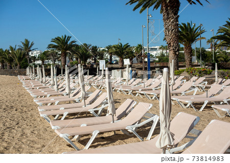 Rows of empty chaise-lounges on the beach in the city of Costa Teguise. Rows of empty chaise-lounges on the beach in the city of Costa Teguise. 73814983