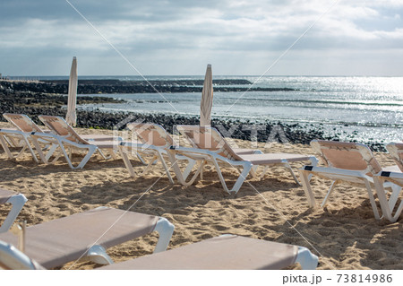 Rows of empty chaise-lounges on the beach in the city of Costa Teguise. Rows of empty chaise-lounges on the beach in the city of Costa Teguise. 73814986