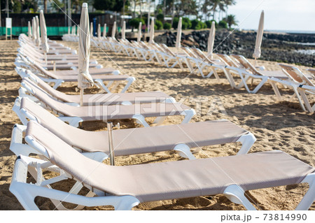 Rows of empty chaise-lounges on the beach in the city of Costa Teguise. 73814990