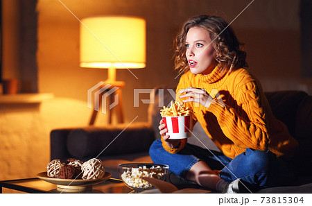 Young female eating French fries and watching interesting movie Young female eating French fries and watching interesting movie 73815304