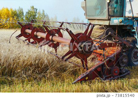 Combine harvester harvests ripe wheat. Concept of a rich harvest. Agriculture image. Combine harvester harvests ripe wheat. Concept of a rich harvest. Agriculture image. 73815540
