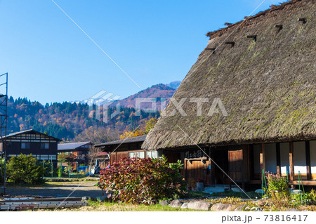 横から見た茅葺き屋根の古民家と奥に広がる山々 岐阜県白川郷の写真