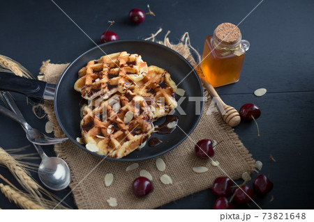 Honey on waffles with cherry berries on dark wooden background. breakfast concept 73821648