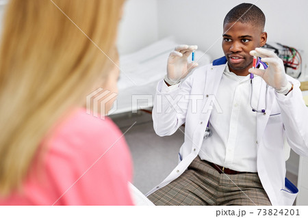 african male doctor have a nice talk with kid girl, showing colourful capsules african male doctor have a nice talk with kid girl, showing colourful capsules 73824201