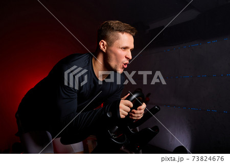young man diligently riding an exercise bike young man diligently riding an exercise bike 73824676