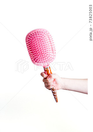 Beautiful pink comb brush in the hand of a girl isolated on a white background 73825003