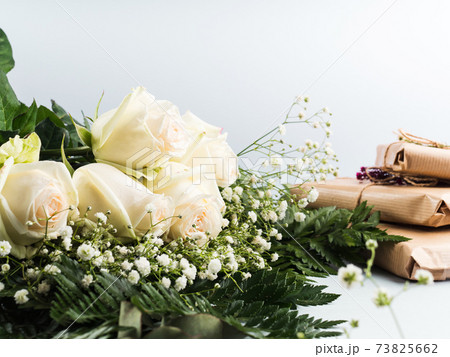 White roses bouquet as gift on a holiday on gray White roses bouquet as gift on a holiday on gray 73825662