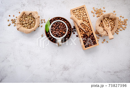 Roasted coffee beans with scoops setup on white concrete background. 73827396