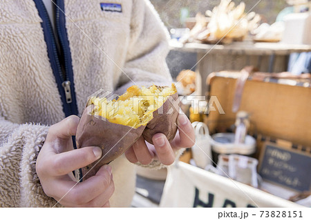 焼きたての焼き芋を半分に割る若い女性手元 73828151