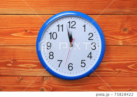 Blue wall clock on a wooden background Blue wall clock on a wooden background 73828422