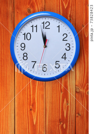 Blue wall clock on a wooden background 73828423