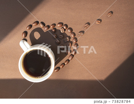White cup of coffee and coffee beans on brown background White cup of coffee and coffee beans on brown background 73828784