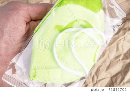 Pack with a respiratory medical mask KN 95 in hand on a background of wrinkled kraft paper. Concept of medical supplies delivery and online purchase 73833702