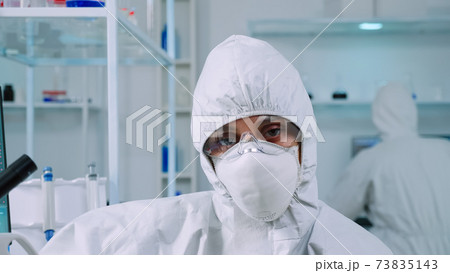 Portrait of tired scientist in coverall looking at camera Portrait of tired scientist in coverall looking at camera 73835143