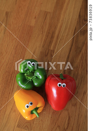 Composition with three color - red, green, yellow fresh sweet pepper or bell pepper with doll's eyes on wooden background. 73836919