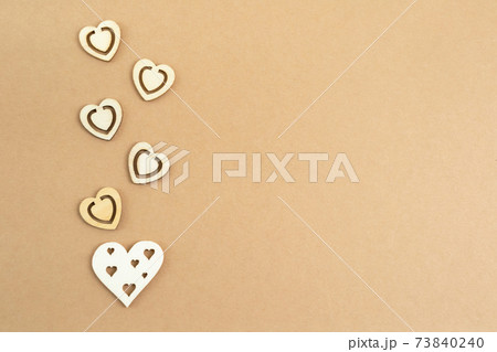 Wooden hearts on a pastel craft paper background. Abstract background with wood cut shapes. Sainte Valentine, mother's day, birthday greeting cards, invitations. Copy space. 73840240