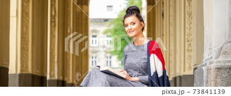 Student with book sitting on stairs Student with book sitting on stairs 73841139
