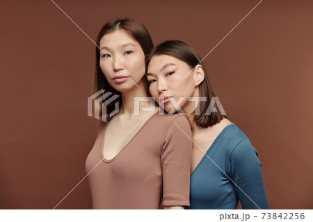 Gorgeous girl of Asian ethnicity keeping head on shoulder of her twin sister 73842256