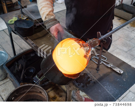 Man Hands Shaping hot glass art piece with wooden tool Man Hands Shaping hot glass art piece with wooden tool 73844698