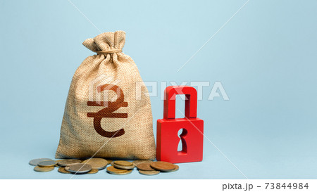 Ukrainian hryvnia money bag and red padlock. Tight government control over the financial system. Cash flow monitoring. Freezing of pension savings. Blocking bank accounts and seizing assets. 73844984