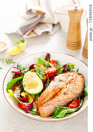 Salmon fish steak grilled, avocado and fresh vegetable salad with tomato, bell pepper and leafy vegetables 73846958