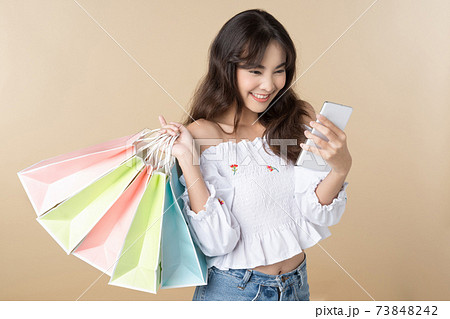 Young Asian woman holding shopping bag using phone  73848242