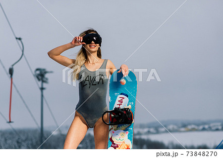 Attractive woman dressed in swimsuit with snowboard on the slope Attractive woman dressed in swimsuit with snowboard on the slope 73848270