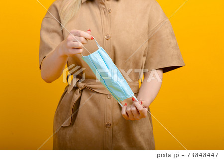 Image of female hands with blue mask on yellow background Healthcare Covid 19 outbreak contamination Image of female hands with blue mask on yellow background Healthcare Covid 19 outbreak contamination 73848447