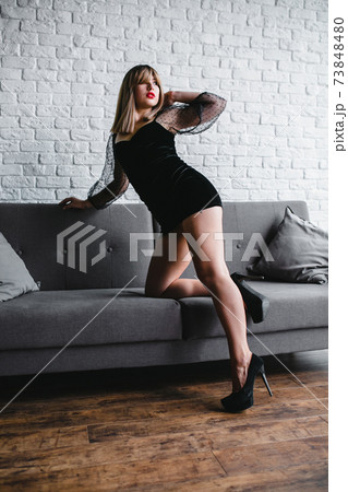 Young sexy blonde with naked legs in high heel shoes posing near the sofa 73848480