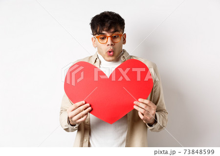 Surprised handsome man receive big red heart postcard on Valentines day, looking at gift with amazement, enjoying lovers day, standing over white background Surprised handsome man receive big red heart postcard on Valentines day, looking at gift with amazement, enjoying lovers day, standing over white background 73848599