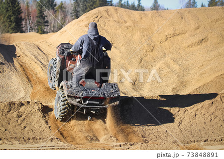 The back of a quader going up a gravel hill 73848891