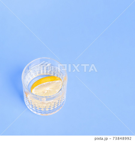 Glass with water and lemon on blue background 73848992